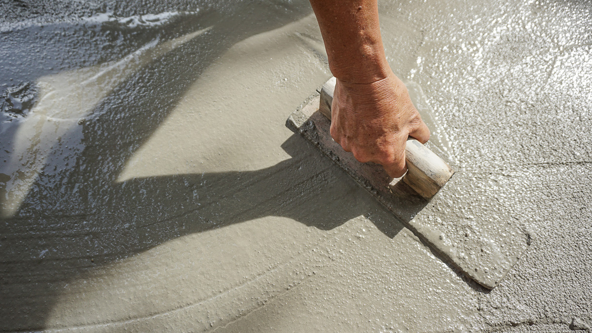 A person laying and smoothing out concrete in El Paso.